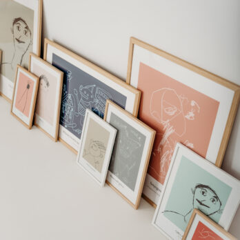 Personalizirani posteri izrađeni od dječjih crteža u različitim bojama i veličinama, uokvireni i naslonjeni na zid.