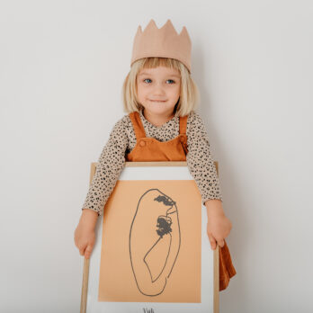 Djevojčica drži veliki personalizirani poster nastao iz dječjeg crteža, u monokromatskom stilu.